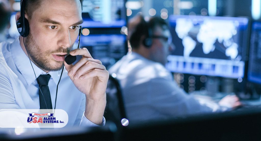 Man monitoring security systems with headset in a control room, focused on screens displaying data, representing USA Alarm Systems' professional monitoring services for San Fernando businesses.