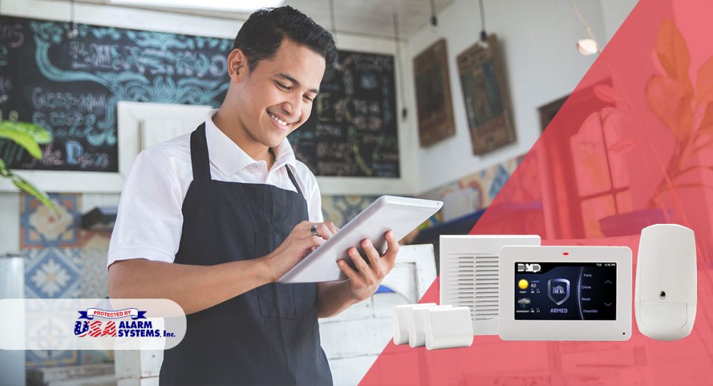 Smiling retail worker using a tablet in a shop, with USA Alarm Systems security panel and equipment displayed, emphasizing professional security solutions for San Fernando businesses.